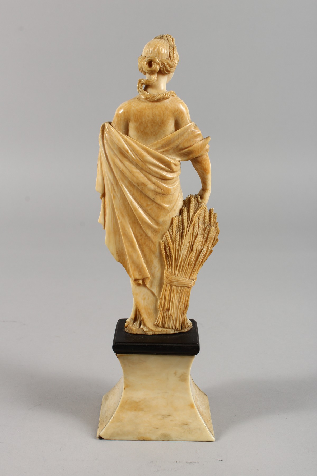 AN 18TH CENTURY CARVED IVORY FIGURE OF A YOUNG FEMALE FIGURE depicting AUTUMN, standing on a plinth. - Image 3 of 5