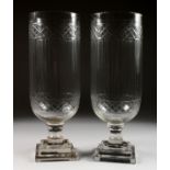 A PAIR OF GLASS STORM LANTERNS with crosshatch and line engraved decoration. 16ins high.