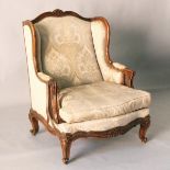 A LATE 19TH CENTURY FRENCH CARVED BEECH FRAMED WING BACK ARMCHAIR, upholstered with a classical