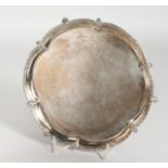 A SMALL ENGRAVED SILVER PLATED WAITER on claw and ball feet. 8ins diameter.
