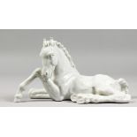 A MEISSEN WHITE GLAZED HORSE LYING DOWN. Crossed swords mark in blue. No. A1195. 8ins long.