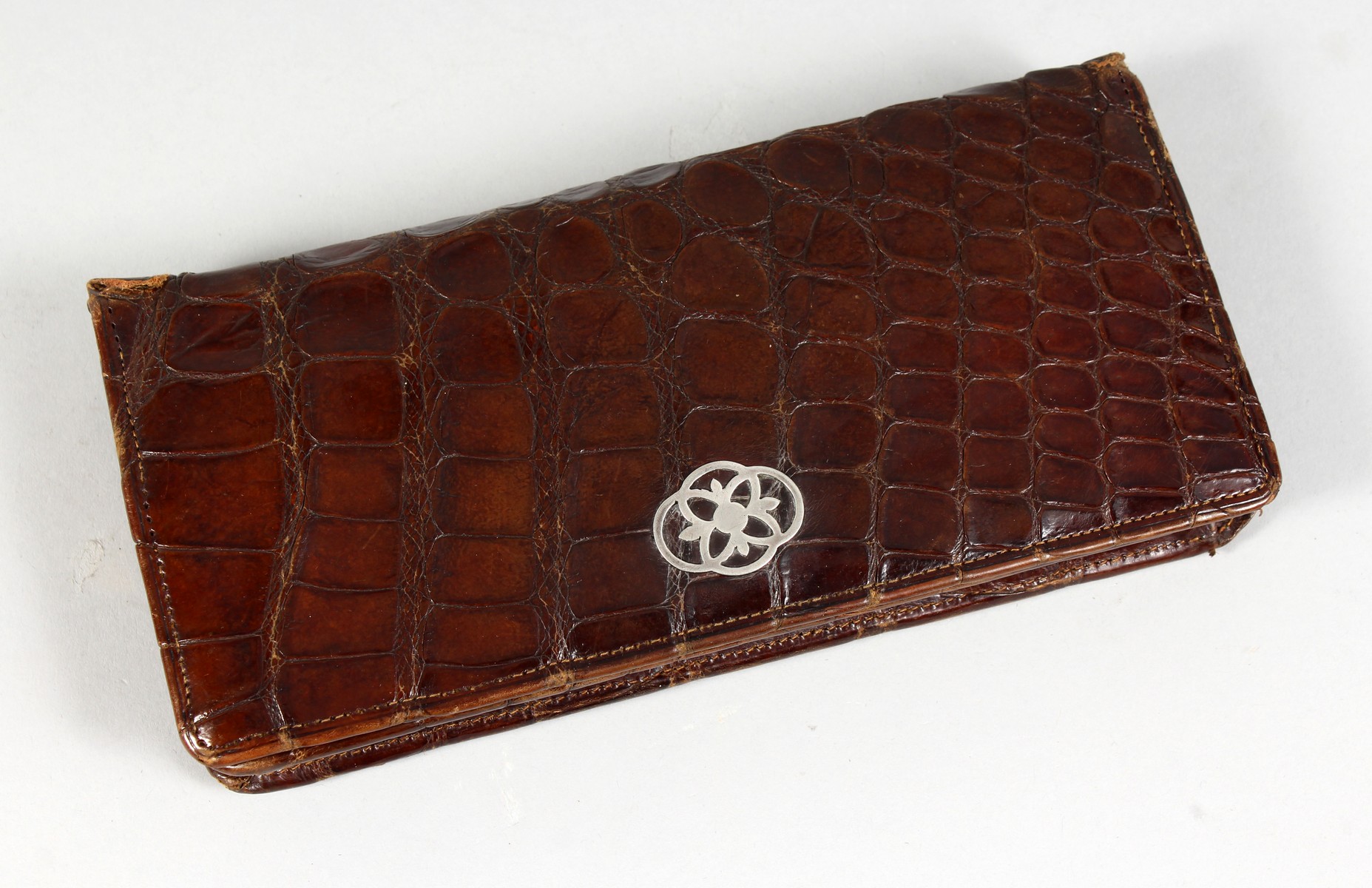 A LADIES CROCODILE LEATHER PURSE, wit silver mount. 8ins long.