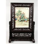 A CHINESE PORCELAIN TABLE SCREEN, in a carved hardwood frame. 26.5ins high x 18ins wide.