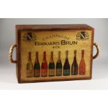 A NOVELTY WOODEN STORAGE BOX the hinged lid decorated with wine bottles. 22ins wide.