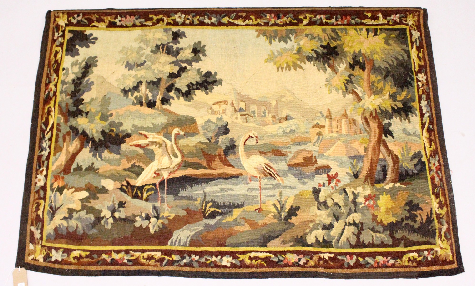 A CONTINENTAL TAPESTRY WALL HANGING with a wooded river landscape, classical ruins and birds. 5ft