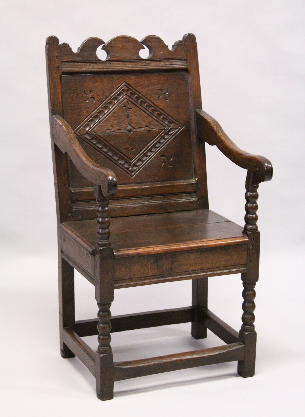 A 17TH CENTURY OAK WAINSCOTT CHAIR, with shaped cresting rail, carved back panel, the solid seat