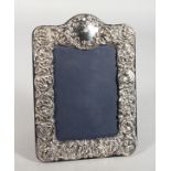 A SILVER PHOTOGRAPH FRAME repousse scrolls and flowers. 8ins x 6ins.