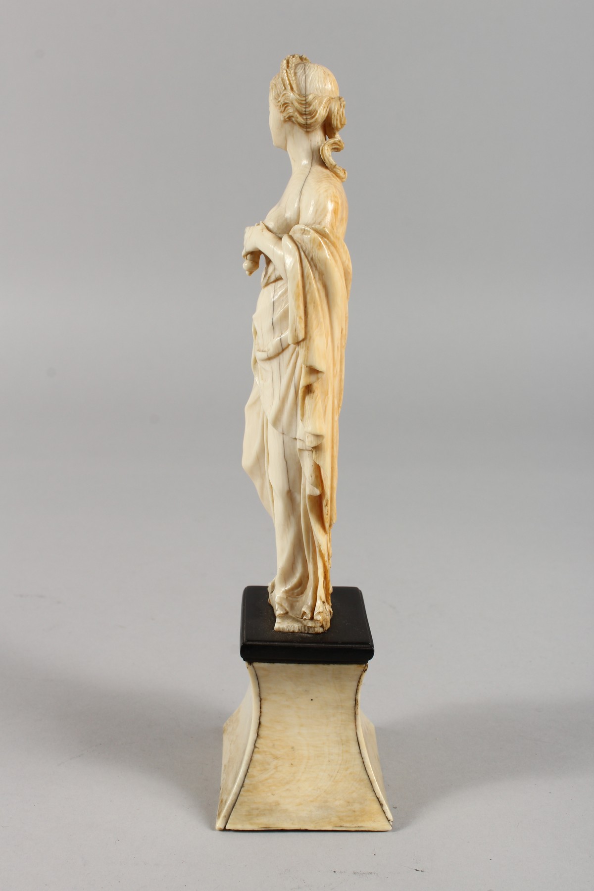 AN 18TH CENTURY CARVED IVORY FIGURE OF A YOUNG FEMALE FIGURE depicting AUTUMN, standing on a plinth. - Image 4 of 5