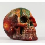 AN AMBER STYLE RESIN MODEL OF A SKULL. 6ins long.