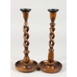 A PAIR OF CIRCULAR WOODEN BARLEY TWIST CANDLESTICKS. 12ins high.