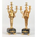 A PAIR OF EMPIRE REVIVAL GILT BRONZE FIGURAL TWIN BRANCH, THREE LIGHT CANDELABRA, on marble bases.