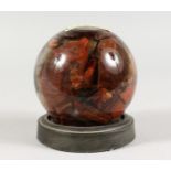 A GLASS BALL containing fifteen million years old petrified rosewood. 4ins diameter.