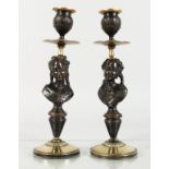 A SMALL PAIR OF PATINATED AND POLISHED BRONZE CANDLESTICKS, the stems cast as bust of young