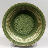 A LARGE CHINESE CELADON PORCELAIN DISH, with moulded dragon decoration. 16ins diameter.