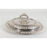 A GOOD PLATED OVAL ENTREE DISH, COVER AND HANDLE, with embossed decoration. 12ins wide.