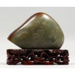 A SMALL JADE SCHOLAR'S ROCK WITH CARVED DECORATION, on a pierced wood stand. 4ins high.