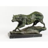 A BRONZE OF A PROWLING WOLF ON A ROCK, mounted on a marble base. 17ins long.