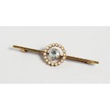 A 15CT GOLD BAR BROOCH, set with a single aquamarine surrounded by a band of pearls. 2.25ins long.