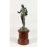 A NEAPOLITAN BRONZE BUST OF NARCISSUS on a circular base. 11ins high on a wooden plinth. 17.5ins