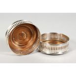 A PAIR OF PIERCED SILVER WINE COASTERS with turned wood bases. 4ins diameter. London 1973.