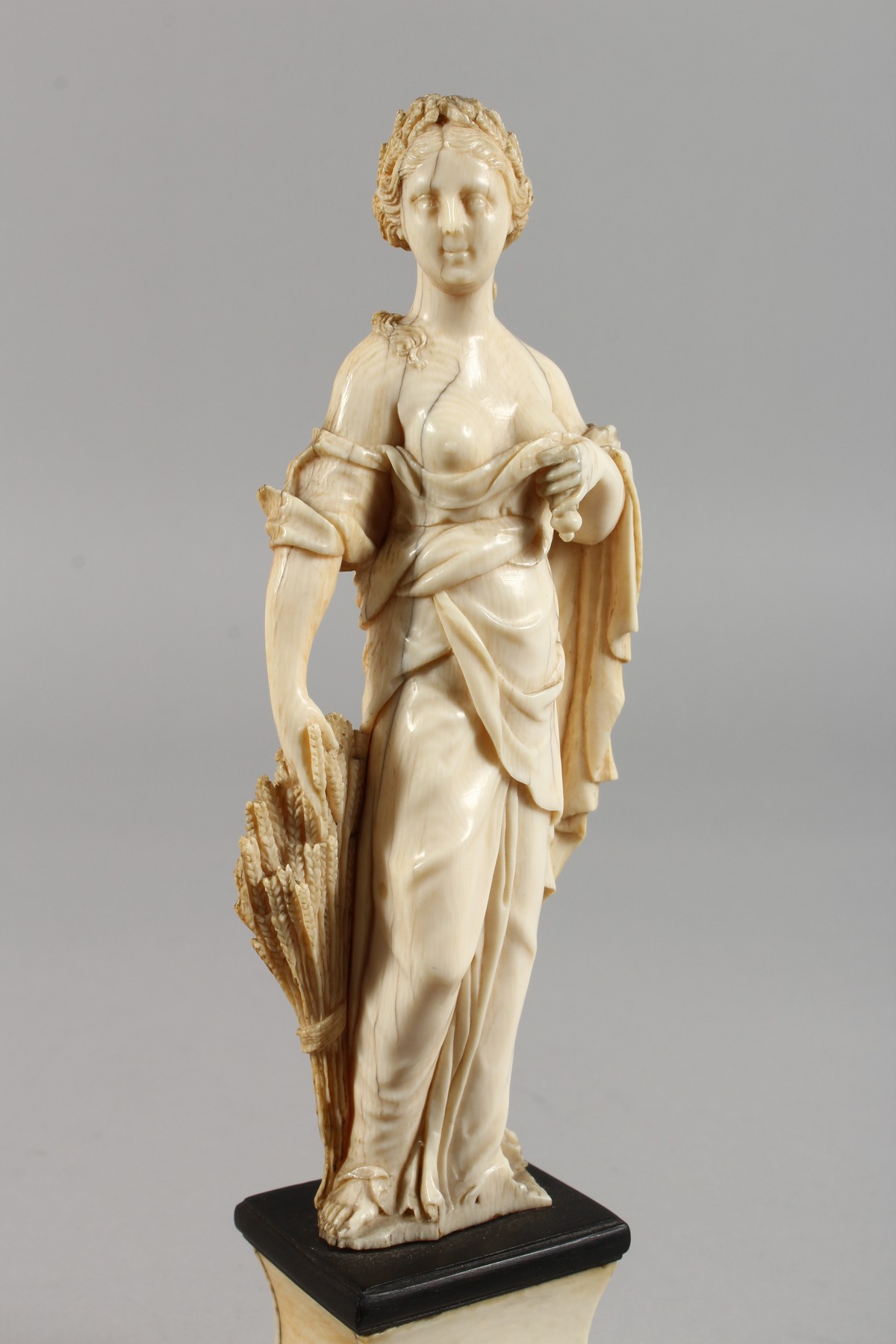AN 18TH CENTURY CARVED IVORY FIGURE OF A YOUNG FEMALE FIGURE depicting AUTUMN, standing on a plinth. - Image 2 of 5