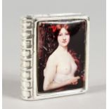 A SILVER BOOK SHAPED PILL BOX, the lid with an enamel semi-nude. 1.5ins diameter.