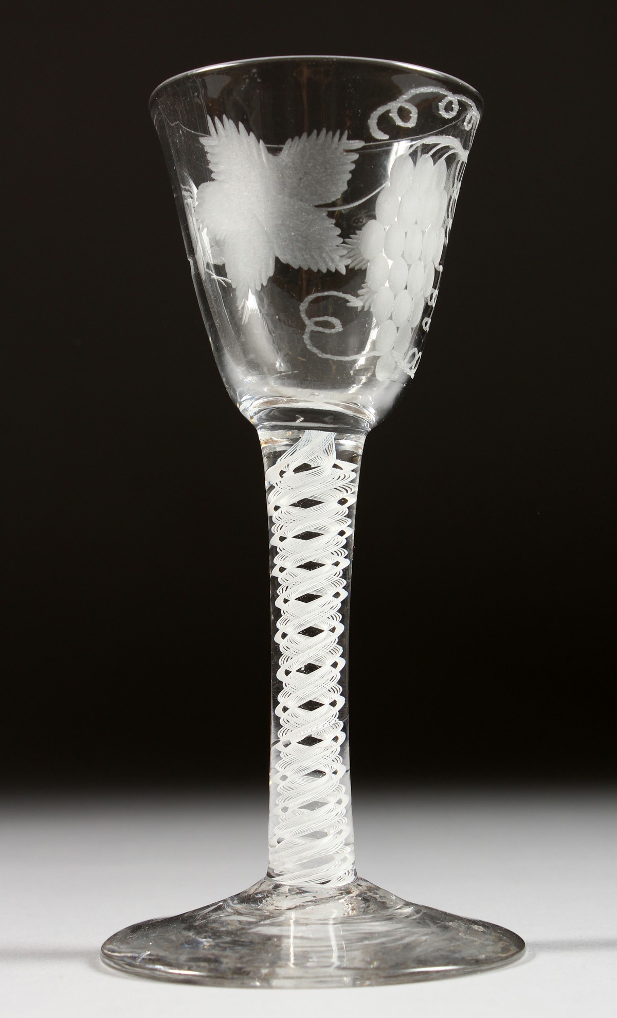 A GEORGIAN WINE GLASS, the bowl engraved with fruiting vines with white twist stem. 5.25ins high.