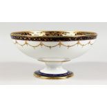 A PORCELAIN PEDESTAL BOWL, in the style of Noritake, painted with swans on a lake. 10ins diameter.