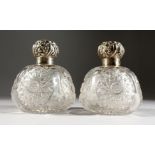 A PAIR OF CUT GLASS CIRCULAR PERFUME BOTTLES with silver tops.