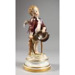 A MEISSEN PORCELAIN FIGURE OF A CHERUB holding a hat and walking with a stick. Cross swords mark
