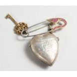 A SILVER HEART SHAPED VESTA on a gold plated pin.