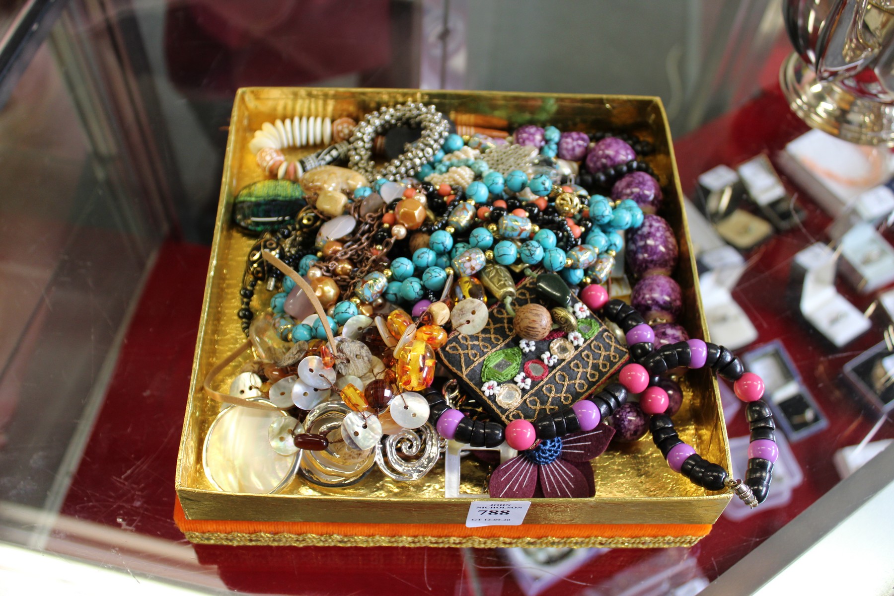 A decorative box containing numerous costume necklaces.