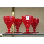 A set of four red glass goblets.