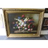 A large and impressive still life of flowers in an urn on a ledge, in a decorative gilt frame.
