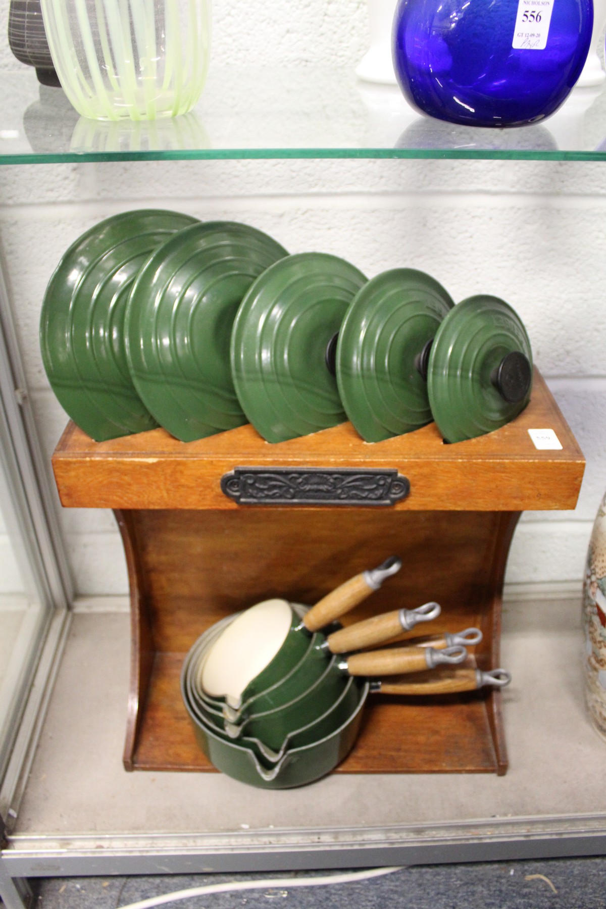 A graduated set of five Le Creuset green cast iron saucepans with lids on original stand.