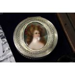 A good continental silver circular box, the hinged lid inset with a painted porcelain plaque of a