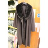 A ladies' full length coat with faux fur collar.