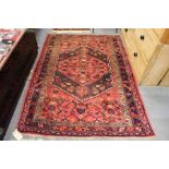 A Persian style rug, red ground with stylized decoration.