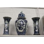 A Dutch Delft style blue and white three piece garniture comprising of a lidded jar and a pair of