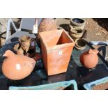 A pair of terracotta bird shaped garden ornaments and a square shaped pot.