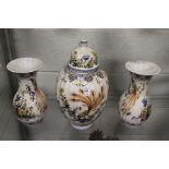 A continental pottery garniture modelled as a lidded jar and a pair of baluster shaped vases, all