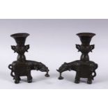 A PAIR OF CHINESE BRONZE ELEPHANT FORMED CANDLE STICKS, each with an object in thier mouth and a