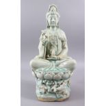 A LARGE CHINESE CELADON CARVED PORCELAIN FIGURE OF GUANYIN, in a seated position upon lotus with