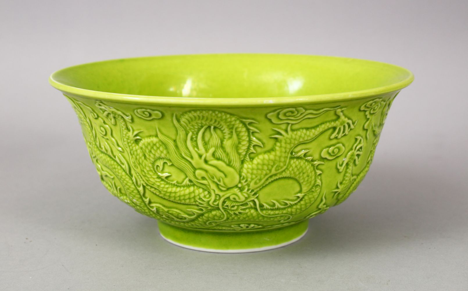 A CHINESE GREEN GLAZED PORCELAIN DRAGON BOWL, with moulded decoration of dragons amongst stylized