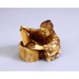 A JAPANESE MEIJI PERIOD CARVED IVORY OKIMONO - the figure seated above his hibachi waving his fan,