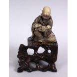 A GOOD CHINESE CARVED SOAPSTONE FIGURE OF LUOHAN & ABALONE SHELL INLAID HARDWOOD STAND, the figure