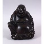 A CHINESE CARVED HARDWOOD / HONGMU FIGURE OF A SEATED BUDDHA, with a humorous expression and one