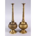 A PAIR OF INDIAN / ISLAMIC BRASS MOULDED ROSE WATER SPRINKLERS, with a ribbed central body, 23cm.