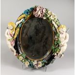 A 19TH CENTURY CONTINENTAL MAJOLICA GLAZED OVAL POTTERY MIRROR, the frame mounted with a pair of