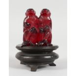 A GOOD CARVED AMBER GROUP OF TWO MONKEYS, 2ins high, on a carved wooden stand.